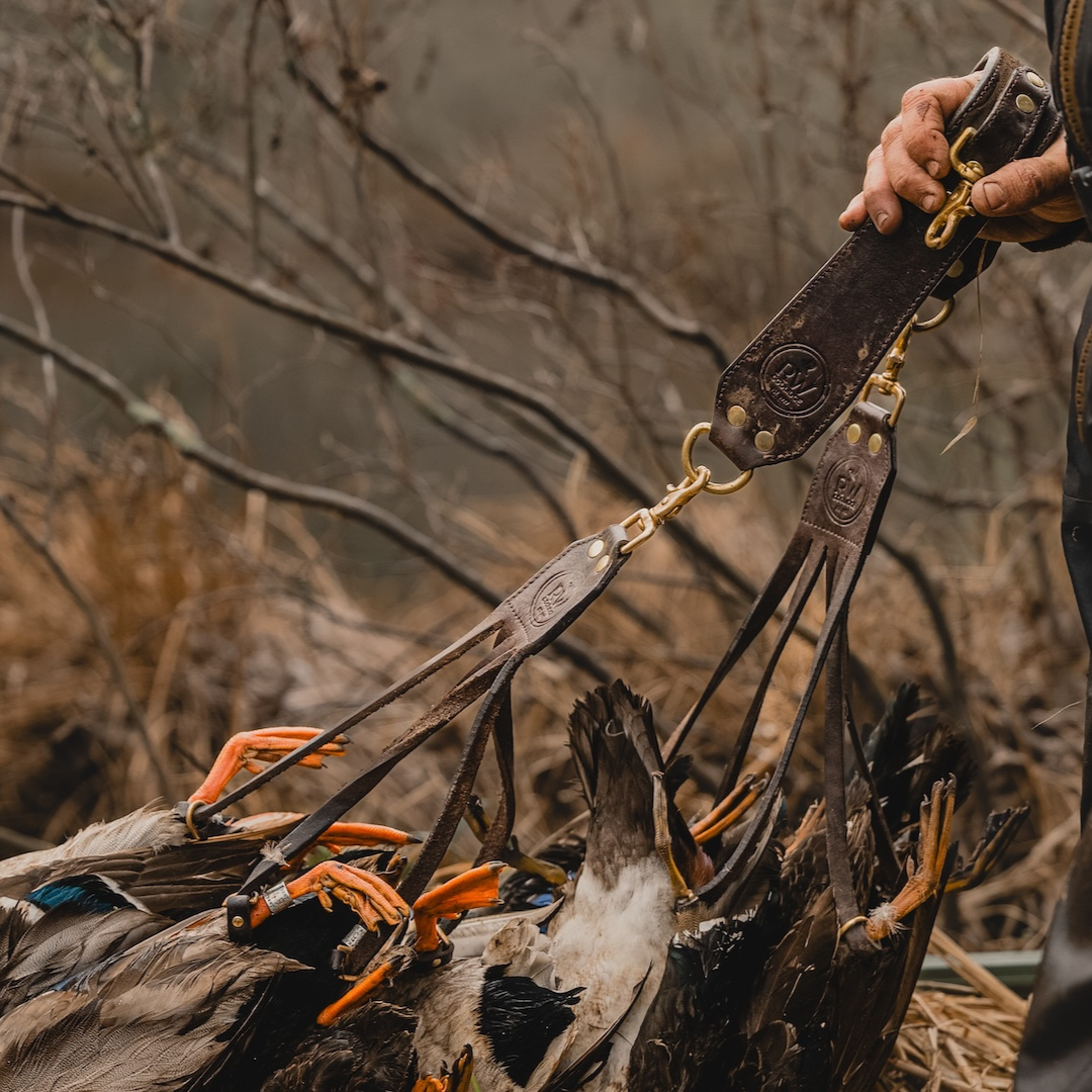 Hunter connecting the two clips of the Leather Duck Strap together in a marsh