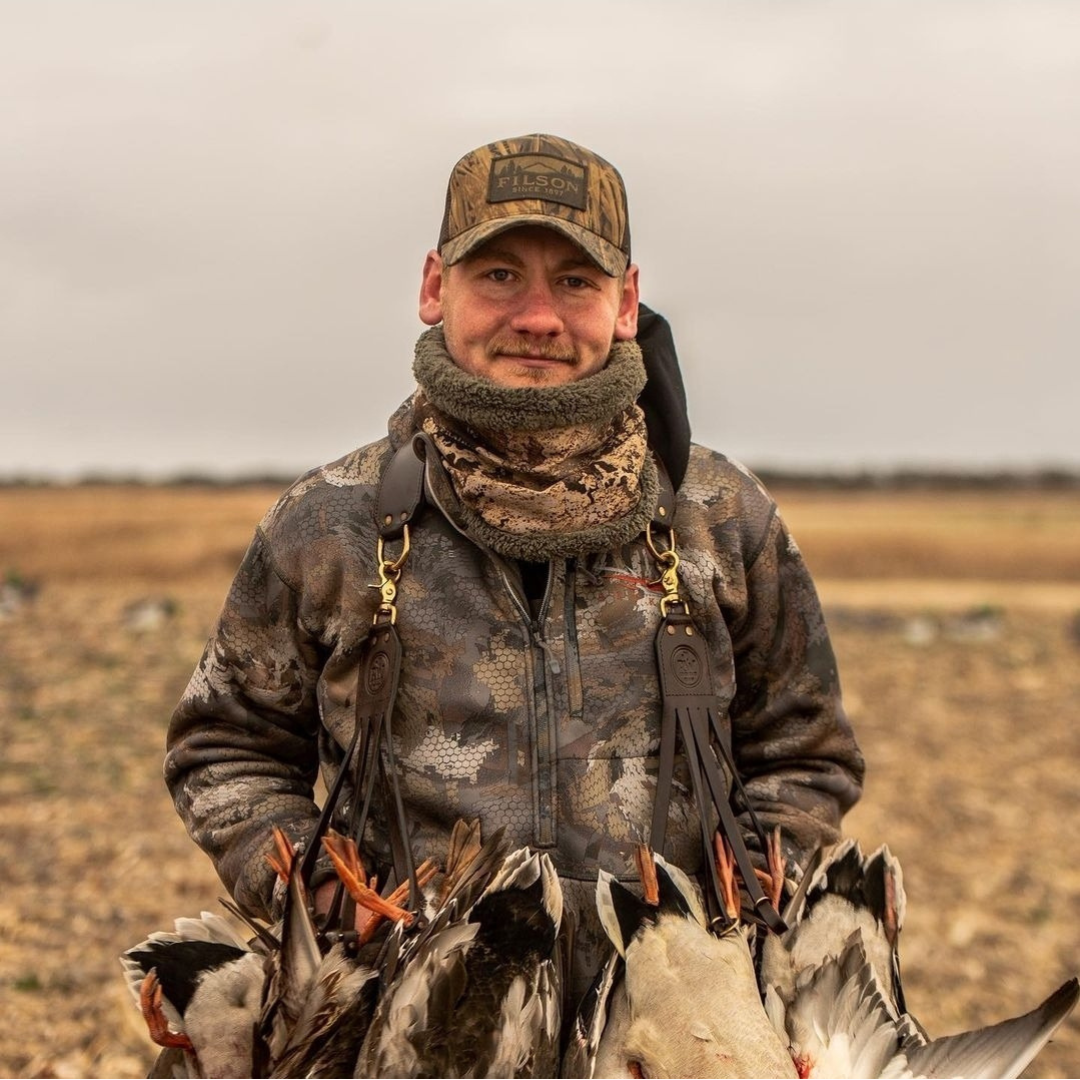 Hunter smiling with a full strap of ducks over both shoulders